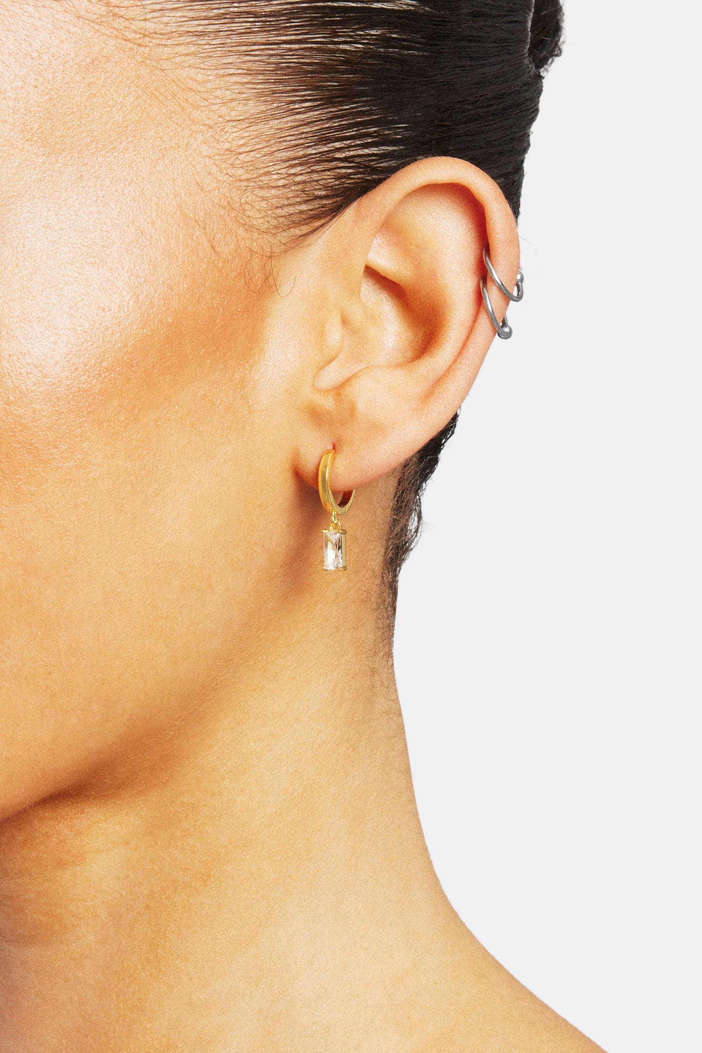 Female model wearing the iced clear gemstone huggie earrings